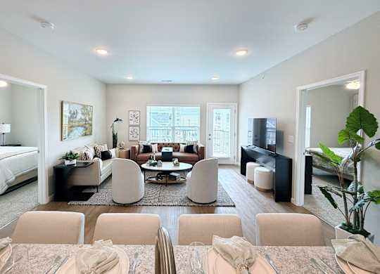 A well-lit, modern living room with a dining area in the foreground.