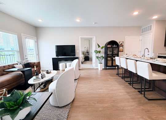 A modern kitchen with white chairs and a wooden floor.