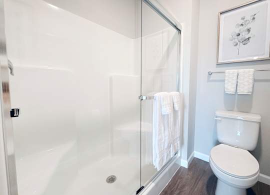 A white toilet sits next to a glass shower stall in a bathroom.