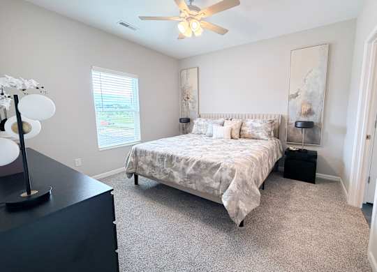 A bedroom with a bed, nightstand, and a ceiling fan.