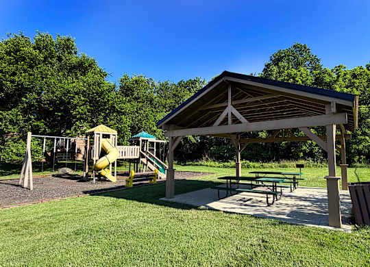 A playground with a wooden shelter and a yellow slide.