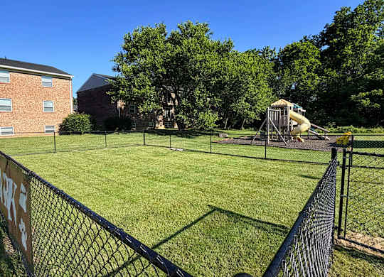 A playground with a slide and a fence in the foreground.