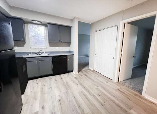A kitchen with a refrigerator, cabinets, and a sink.