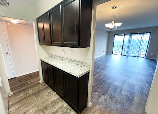 an empty living room and kitchen with dark cabinets and a counter top