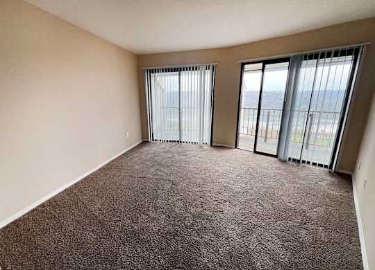 an empty living room with large windows and carpeting  at Indian Lookout Apartments, Cincinnati, OH