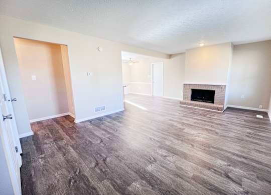 A room with a fireplace and wood flooring.