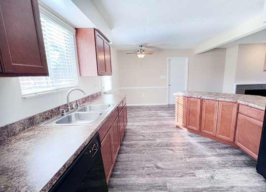 A kitchen with brown cabinets and a black fridge.