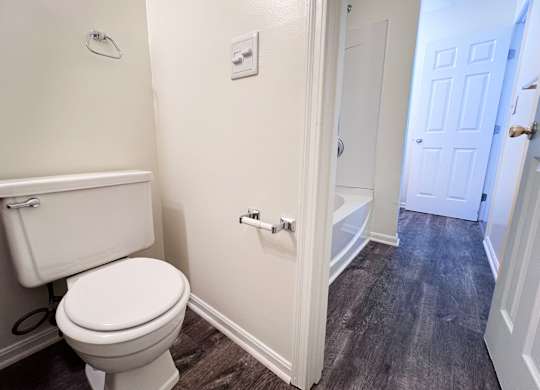 A white toilet in a small bathroom with a white door.
