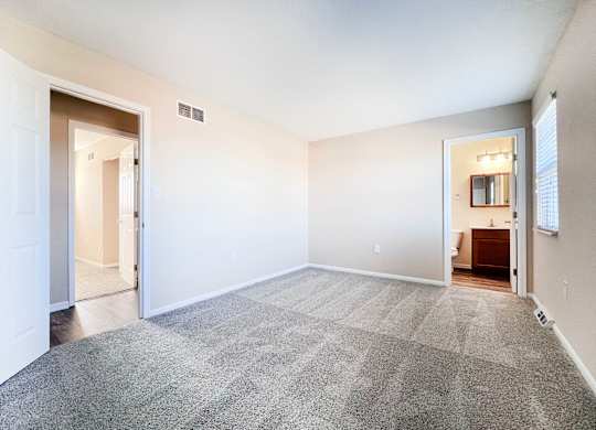 A spacious room with a carpeted floor and white walls.