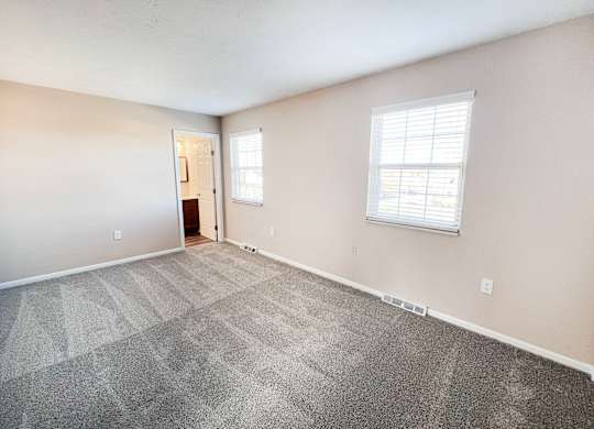 A room with a carpeted floor and a window with blinds.