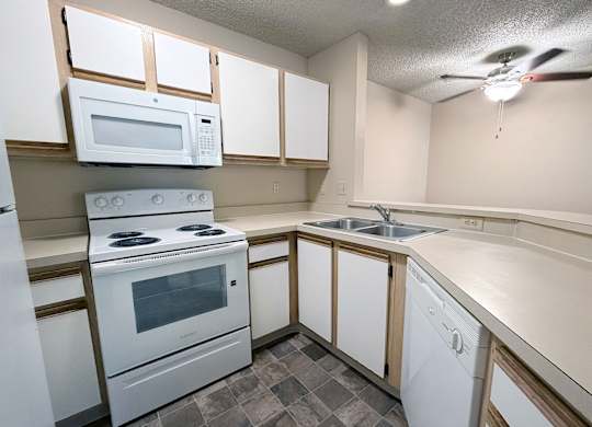 A kitchen with white appliances and wooden cabinets.