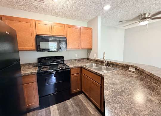 A kitchen with black appliances and wooden cabinets.