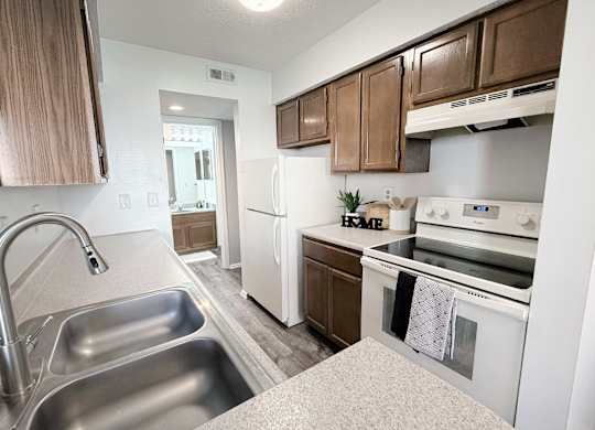 A kitchen with a stainless steel sink and white appliances.