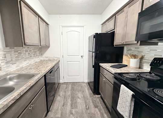 A kitchen with black appliances and wooden cabinets.