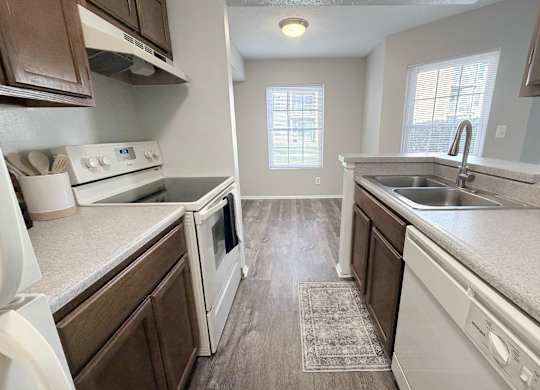 A kitchen with white appliances and brown cabinets.