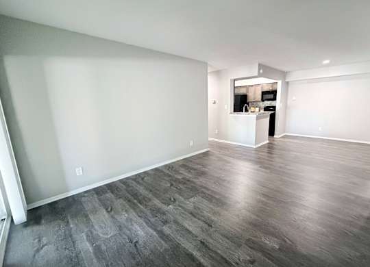 A spacious room with wooden flooring and white walls.