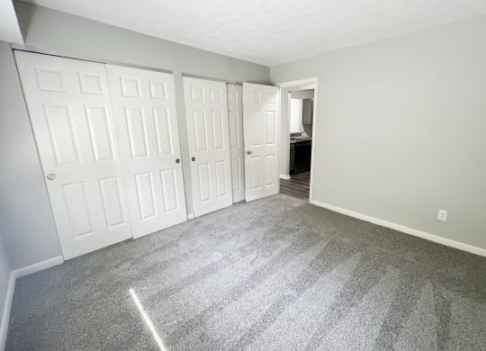 an empty bedroom with white doors and carpeting at Fox Run Apartments, Cincinnati