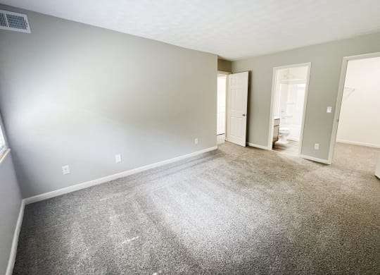 an empty living room with carpet and a door to a bathroom at Fox Run Apartments, Cincinnati