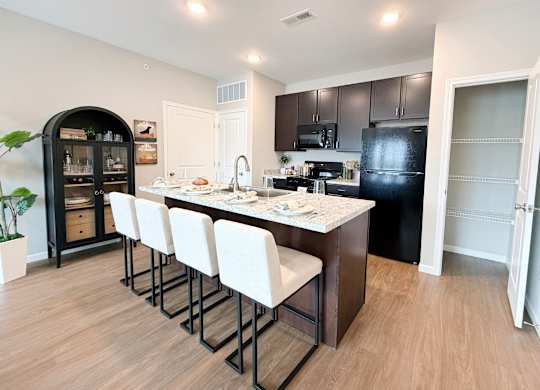 Kitchen island with white bar stools and granite countertop at The Meridian on 32 Apartments, Batavia, 45103
