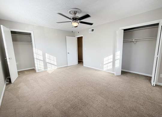 A room with a ceiling fan and carpeted floor.