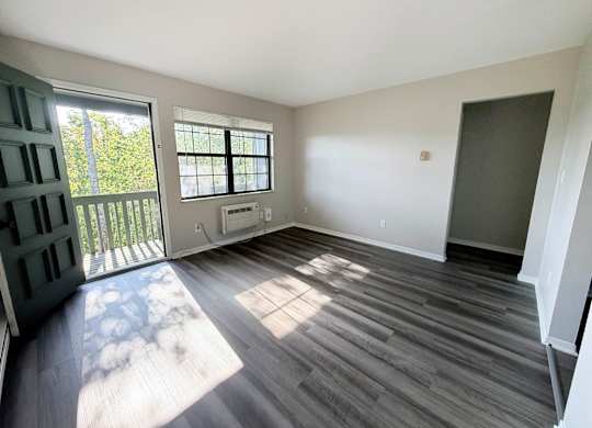 A room with a sliding glass door leading to a balcony.