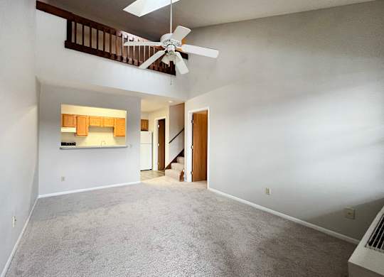 A room with a ceiling fan and a staircase.