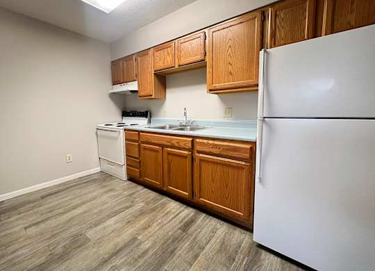 A kitchen with a white refrigerator, wooden cabinets, and a white stove top oven.