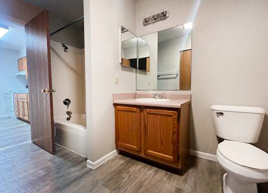 A bathroom with a toilet, sink, and mirror.