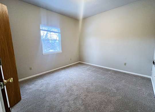 A room with a carpeted floor and a small window.