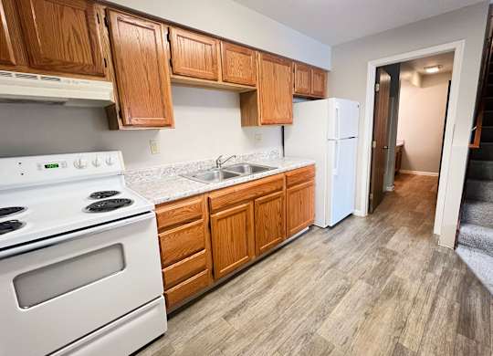 A kitchen with wooden cabinets and a white stove.