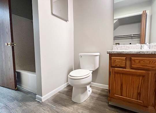 A white toilet in a bathroom with wooden cabinets.