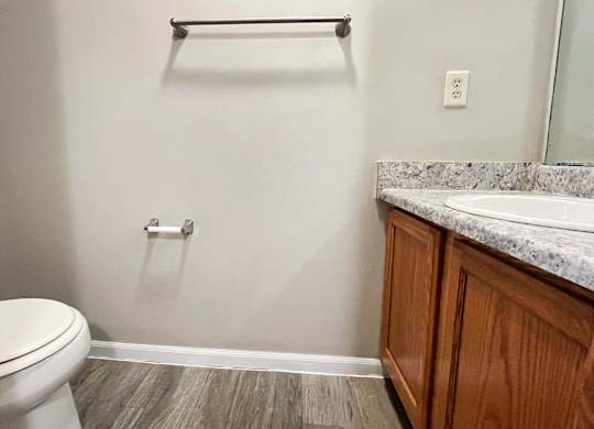 A bathroom with a toilet, a sink, and a towel bar.