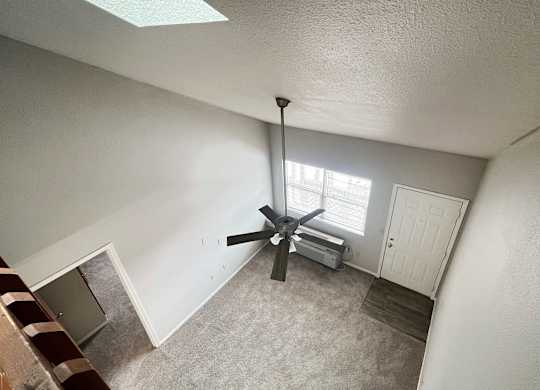 A room with a ceiling fan and a window.