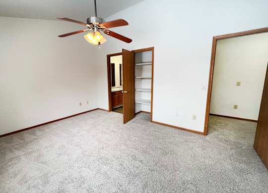 A room with a ceiling fan and carpeted floor.