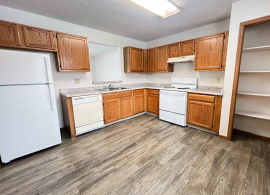 A kitchen with white appliances and wooden cabinets.