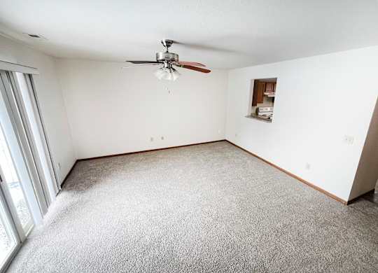 A room with a ceiling fan and carpeted floor.