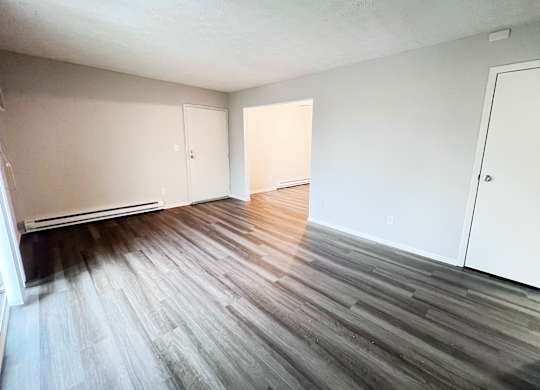 A room with wooden flooring and white walls.