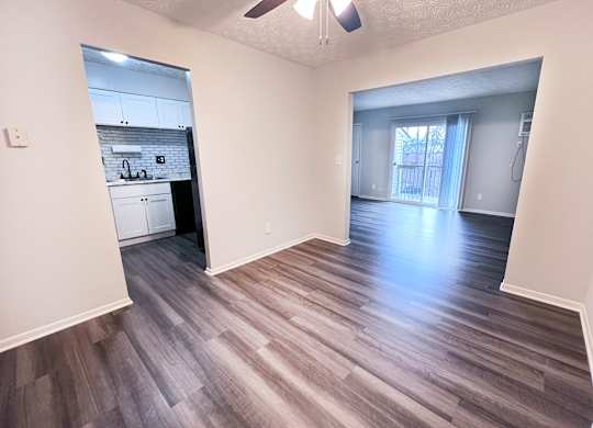 A room with a ceiling fan and wooden flooring.
