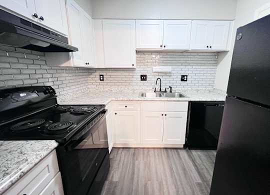 A kitchen with black appliances and white cabinets.