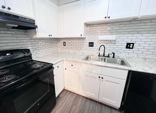 A kitchen with a black stove top oven and white cabinets.