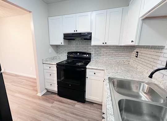 A kitchen with white cabinets and a black dishwasher.