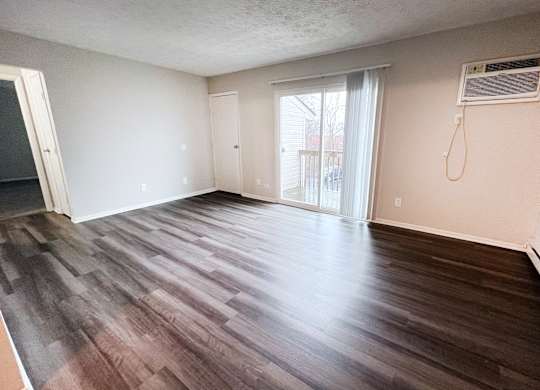 A room with wooden flooring and a window with blinds.