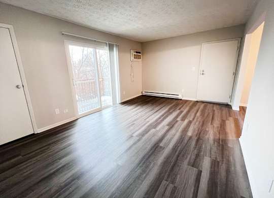 A room with wooden flooring and white walls.