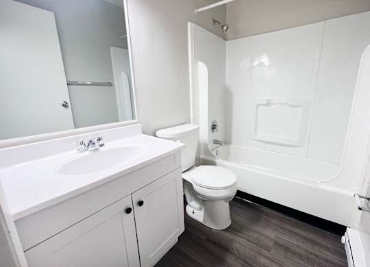 A white bathroom with a toilet, sink, and bathtub.