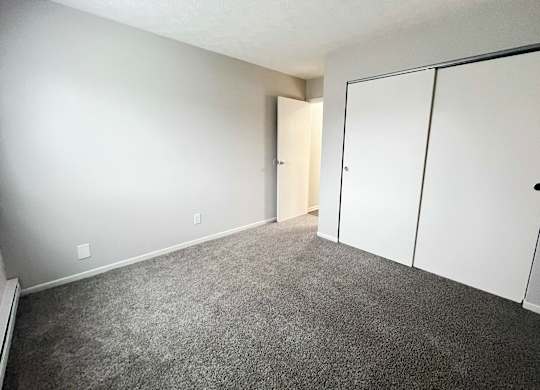 A room with a carpeted floor and a white door.