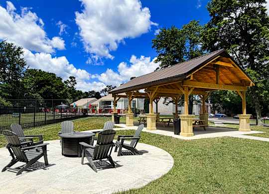 A pavilion with a table and chairs is surrounded by a grassy area.