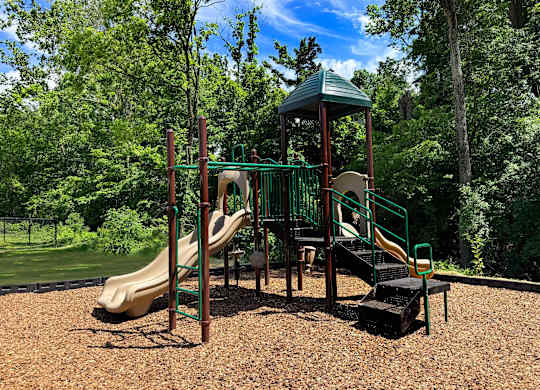 A playground with a green slide and a yellow slide.
