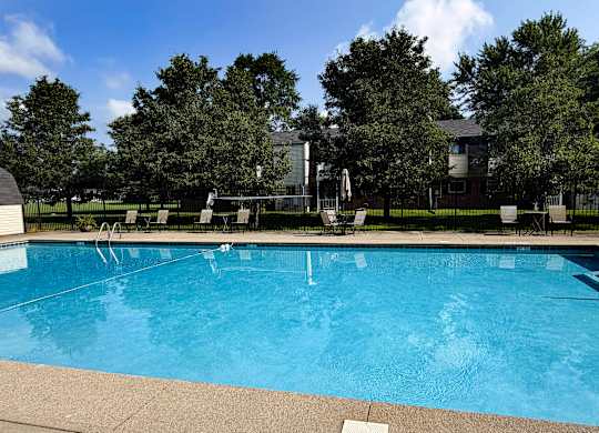 A large swimming pool surrounded by trees and a building in the background.