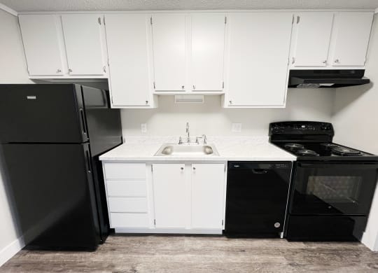 a kitchen with white cabinets and black appliances and a black refrigerator  at Wentworth Estates Apartments, Florence, Kentucky