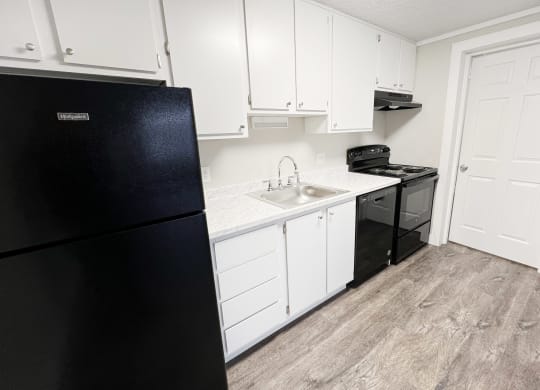 a kitchen with white cabinets and a black refrigerator  at Wentworth Estates Apartments, Florence, Kentucky